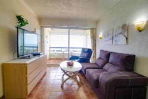 ein Wohnzimmer mit einer Couch, einem Fernseher und einem Tisch in der Unterkunft Ferienwohnung am Strand - 2 Schlafzimmer in Arguineguín
