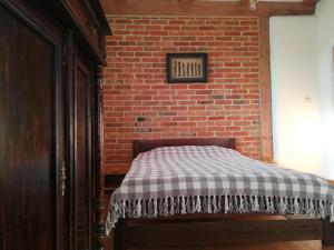 a bed in a room with a brick wall at Noclegi w domu szachulcowym dla dwóch osób in Ustka