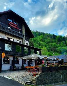 a building with a table and umbrella in front of it at Gościniec Salmopolski in Szczyrk