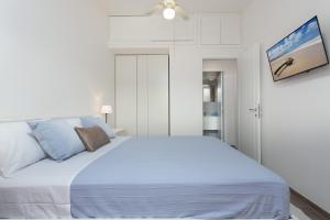 een witte slaapkamer met een groot bed met blauwe kussens bij Sa Prenda in Villasimius