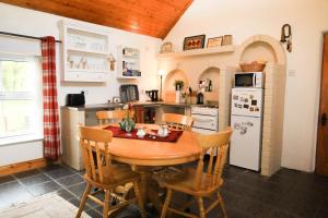 a kitchen with a wooden table and chairs in a kitchen at Wisteria Cottage in Ballyconnell