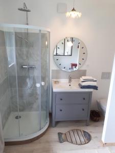 ein Bad mit einer Dusche, einem Waschbecken und einem Spiegel in der Unterkunft L’escale côté jardin in Saint-Laurent-de-Médoc