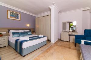 ein Schlafzimmer mit einem Bett und einem blauen Stuhl in der Unterkunft Dalyan Hotel Nish Caria in Dalyan