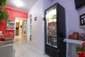 a large black refrigerator in a hallway with red walls at Pousada Tia Eni in Gramado