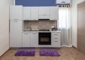 a kitchen with white cabinets and purple mats on the floor at Casa vacanze Biondo in Trappeto