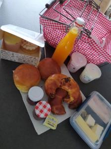a table topped with donuts and a basket of orange juice at Les moineaux du Lileau in Marchin