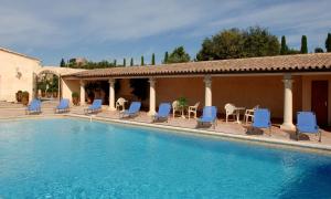 a swimming pool with blue chairs and a house at La Bergerie in Joucas