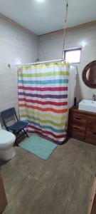 a bathroom with a shower curtain and a toilet at Casa de Adobe in Isla de Maipo