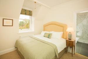 a white bedroom with a bed and a window at Springkell in Eaglesfield