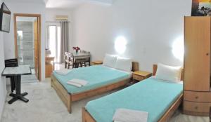 a bedroom with two beds and a dining room with a table at Egeon Rooms and Studios in Georgioupolis