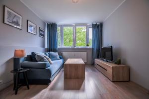 a living room with a blue couch and a tv at CITYSTAY Partyzantow Apartment in Gdynia