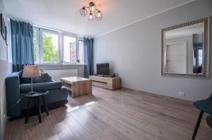 een woonkamer met een blauwe bank en een spiegel bij CITYSTAY Partyzantow Apartment in Gdynia