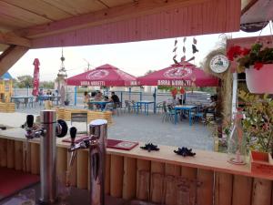 eine Bar mit roten Sonnenschirmen, Tischen und Stühlen in der Unterkunft Andreea Residence Mamaia Nord in Mamaia Nord – Năvodari