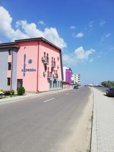 ein rosafarbenes Gebäude am Straßenrand in der Unterkunft Andreea Residence Mamaia Nord in Mamaia Nord – Năvodari