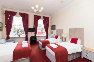 two beds in a hotel room with red carpet at Edinburgh Rays Guest House in Edinburgh