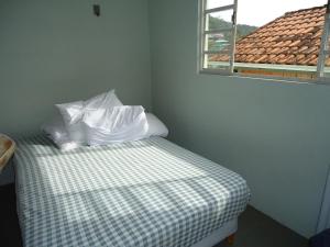 Un dormitorio con una cama con almohadas blancas y una ventana en Casa Floripa na Barra da Lagoa, en Florianópolis