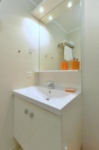 een witte badkamer met een wastafel en een spiegel bij Orange Studio Paris Disneyland in Serris