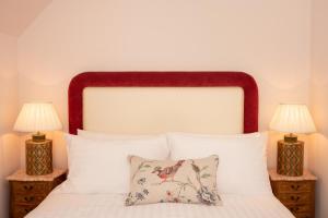 a bedroom with a white bed with two lamps at Springkell in Eaglesfield