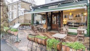 un patio con mesas y sillas fuera de un restaurante en STUNNING GROUND FLOOR GARDEN APARTMENT - Entire Apartment, Centrally Located, With Free Off Road Parking By Flat & Wiffi, Beautifully Secluded, 3 mins From All Amenities, en Londres