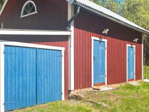 a red and blue barn with two blue doors at 6 person holiday home in TRANSTRAND in Transtrand