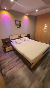 a large bed in a bedroom with pink lights at Apartament Butterfly Mamaia Intrare in Constanţa