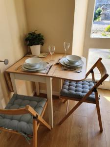 una mesa de madera con 2 sillas, platos y copas de vino en Cosy peaceful one-bedroom cottage in Pitlochry, en Pitlochry