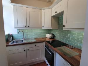 a kitchen with white cabinets and a sink at Cosy peaceful one-bedroom cottage in Pitlochry in Pitlochry