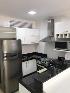 Una cocina con gabinetes blancos y un refrigerador de acero inoxidable. en Apartamento, Apart Hotel, 02 Quartos - Arraial do Cabo, en Arraial do Cabo
