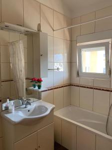 a bathroom with a sink and a tub and a window at Pansion Villa Bubalo in Mostar