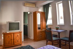 - un salon avec une télévision, une table et des chaises dans l'établissement Apartments Argiroski, à Ohrid