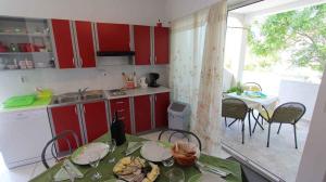 a kitchen with red cabinets and a table and chairs at Apartment Klimno 1 in Klimno