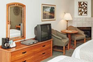a hotel room with a television on a dresser with a mirror at The Grand Hotel Nanaimo in Nanaimo