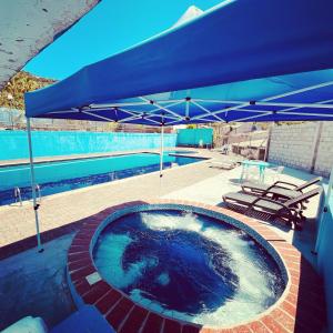 - une piscine avec un parasol bleu et des chaises dans l'établissement Hostería Vista Del Valle, à Hacienda Santa Isabel