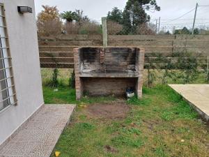 un banco de madera sentado en un patio junto a una valla en arrayanes en Junín