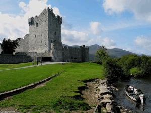 a castle with a boat in front of it at Killarney Towers Hotel & Leisure Centre in Killarney