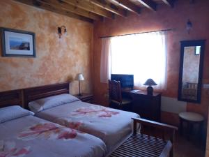 sypialnia z 2 łóżkami, biurkiem i oknem w obiekcie Casa Maria w mieście Agulo