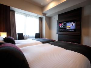 a hotel room with four beds and a flat screen tv at S-peria Hotel Kyoto in Kyoto +23 photos