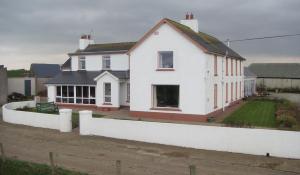 a white house with a fence in front of it at Carnside Guest House in Bushmills