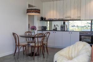 uma cozinha com mesa e cadeiras e uma cozinha com armários brancos em The Cottages at Lake Hayes em Queenstown