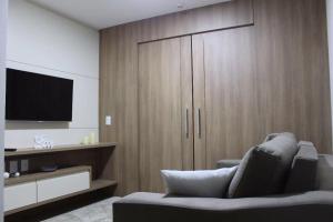 a living room with a large wooden cabinet with a television at Flat em Vista Azul Hotel in Pedra Azul