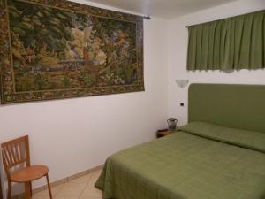 Un dormitorio con una cama verde y una pintura en la pared en Le Palme Bed And Breakfast, en Briatico