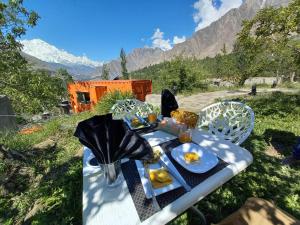 a picnic table with food on it with mountains in the background at Grapes Garden Resort Hunza in Hunza