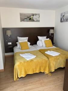 a bedroom with two beds with yellow and white sheets at Hôtel Le Saint Patrice in Bayeux