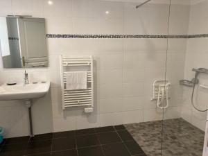 een witte badkamer met een wastafel en een douche bij Hôtel Le Saint Patrice in Bayeux