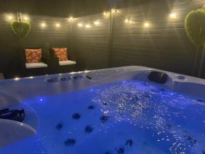 a large tub with blue water in a room with lights at Hot Tub 9 The Fairways in Alnwick