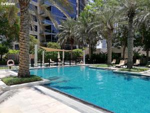 a swimming pool with palm trees and a building at bnbmehomes - Cosy apt, a short stroll away from Dubai Mall - 2004 in Dubai
