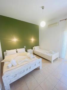 een slaapkamer met 2 bedden en een groene muur bij Diana Studios in Pefki