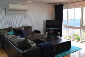 ein Wohnzimmer mit einem Ledersofa und einem Flachbild-TV in der Unterkunft Ocean Breeze in Port Moonta