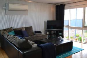 a living room with a leather couch and a flat screen tv at Ocean Breeze in Port Moonta