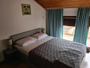 a bedroom with a bed with blue curtains and a window at Guest House Lambovi in Nesebar +3 photos